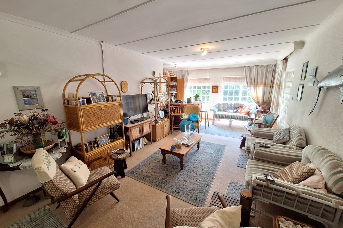 A spacious living room featuring large windows that provide ample natural light, finished with carpeted flooring and a tiled ceiling.
