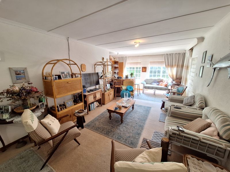 A spacious living room featuring large windows that provide ample natural light, finished with carpeted flooring and a tiled ceiling.