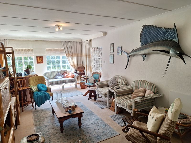 A spacious living room featuring large windows that provide ample natural light, textured ceilings, and neutral carpeting throughout the area.