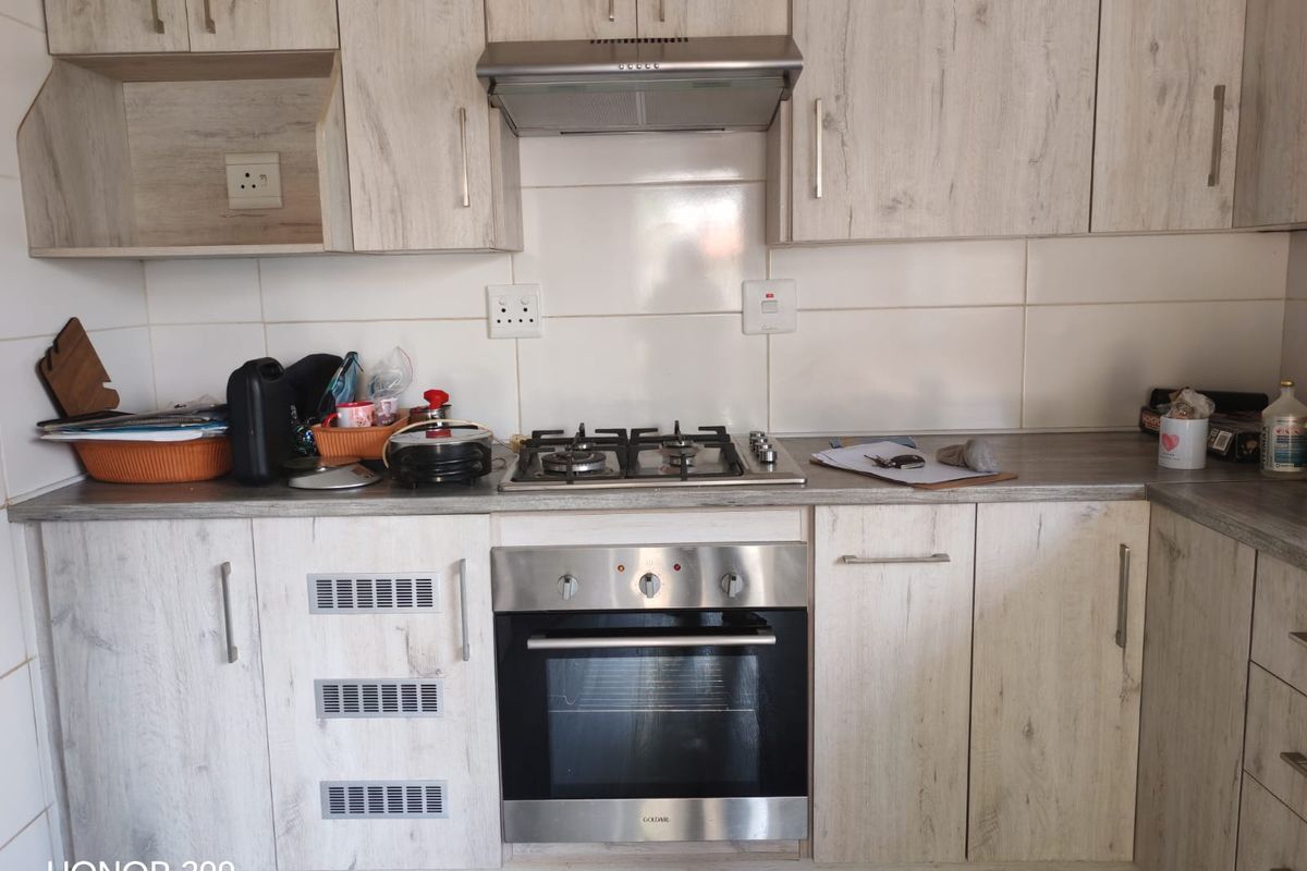 A functional kitchen featuring light wood-grain cabinetry, a built-in gas hob, an oven, and a tiled splashback with ample counter space.