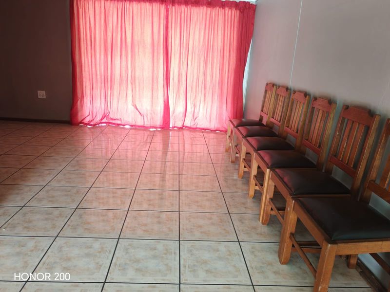 A living area featuring neutral ceramic floor tiles and a large sliding door covered by red curtains.