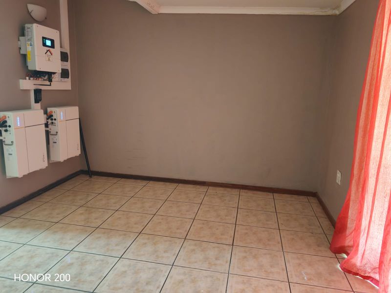 A utility space featuring tiled flooring and a wall-mounted solar inverter and battery storage system.