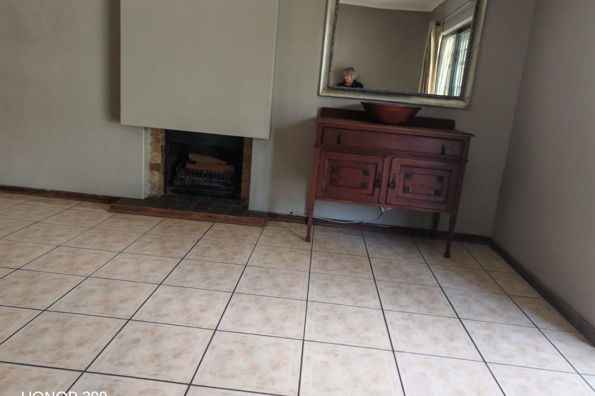 A living room featuring a built-in fireplace and neutral ceramic floor tiles, offering a blank canvas for interior design.