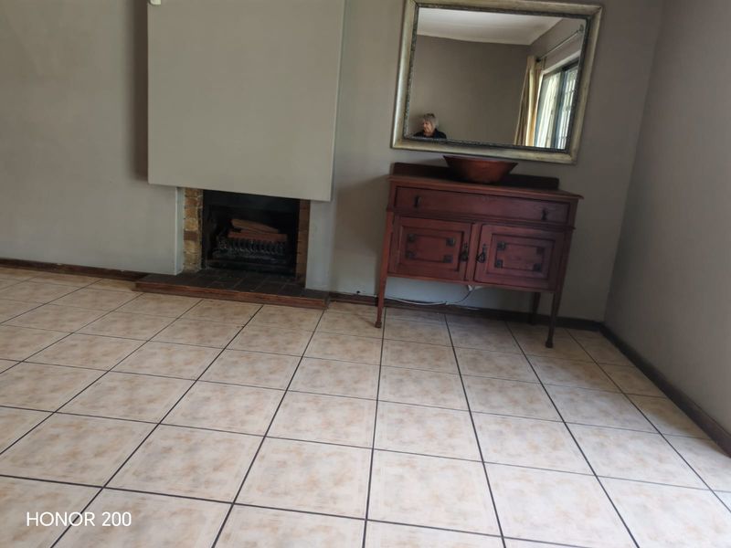 A living room featuring a built-in fireplace and neutral ceramic floor tiles, offering a blank canvas for interior design.