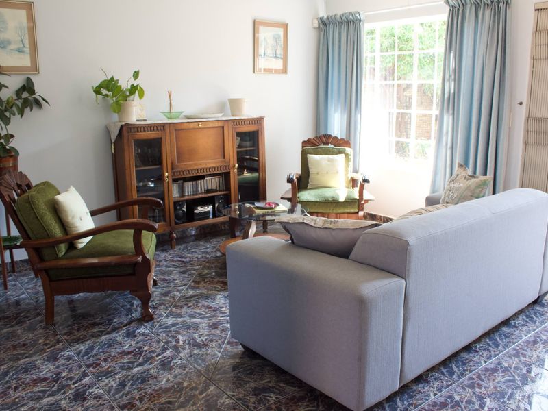 A living room featuring dark patterned tiled flooring and natural light from a large window and glass pane door.