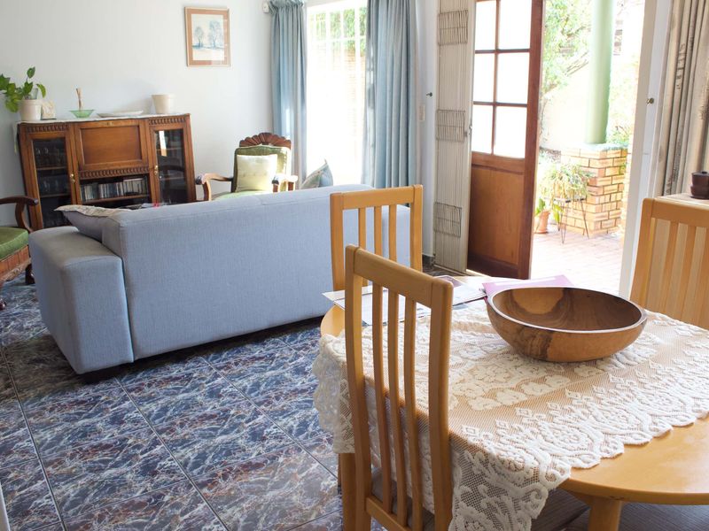 Open plan living and dining area featuring tiled flooring and direct access to an outdoor patio through a timber framed glass door.