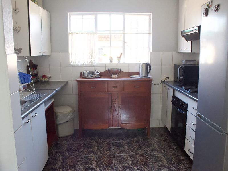 A functional kitchen featuring white cabinetry, dark laminate countertops, tiled backsplash, and built-in oven with extractor fan.