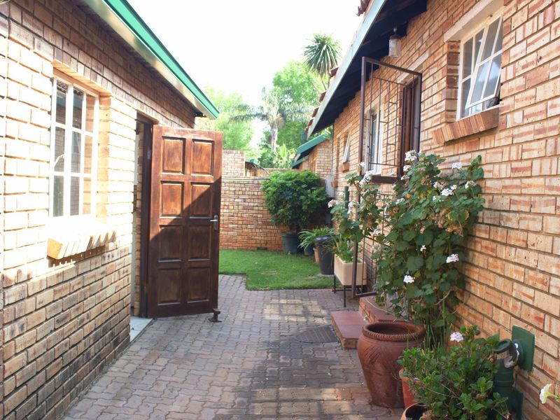 A private rear courtyard featuring brick exterior walls, paved flooring, and a secure entrance, providing a functional outdoor space between building sections.