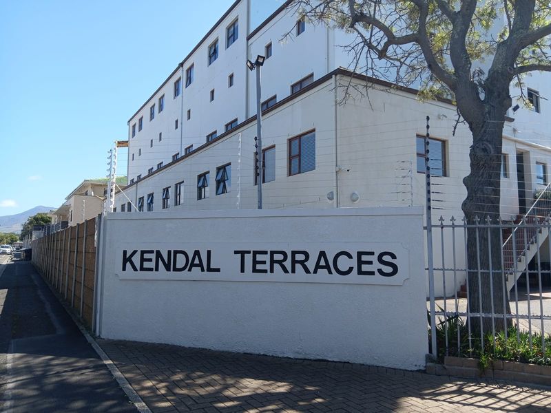 Exterior view of Kendal Terraces apartment complex featuring a secure perimeter wall, electric fencing, and paved entrance area.