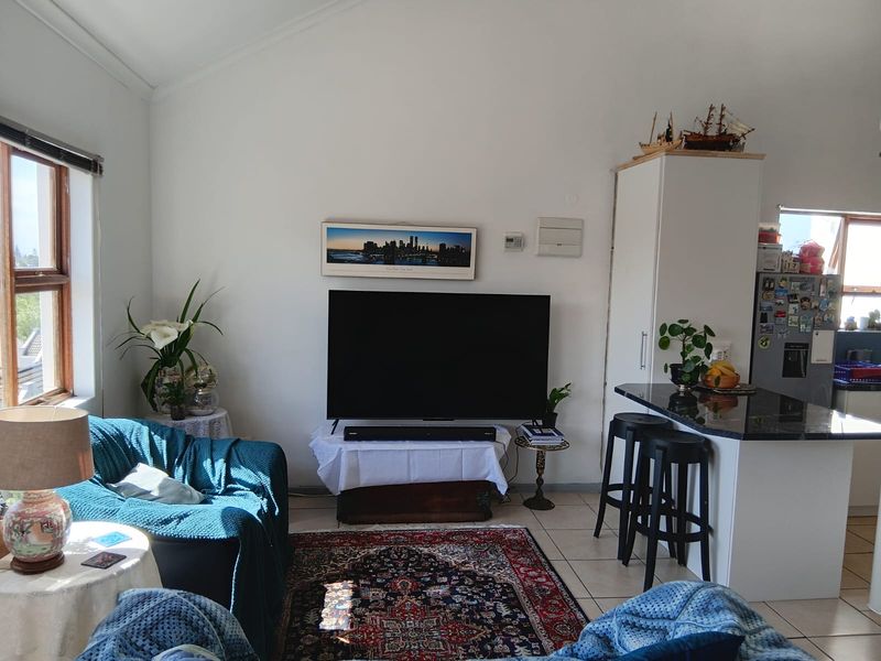 Open-plan living area featuring tiled flooring, a breakfast bar with granite countertops, and a vaulted ceiling, creating a functional and connected living space.