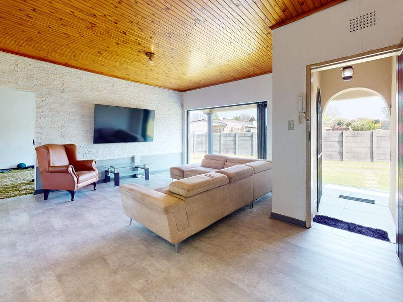 Spacious living room featuring a timber ceiling, stone-clad feature wall, and direct access to the outdoor area through a sliding glass door.
