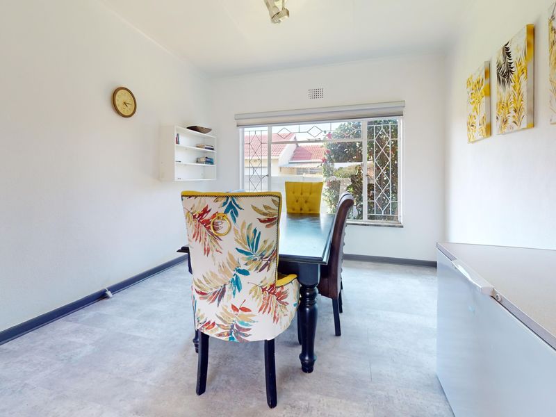 A bright dining room featuring tiled flooring, built-in shelving, and a large window with a security gate, offering a clean and functional space.