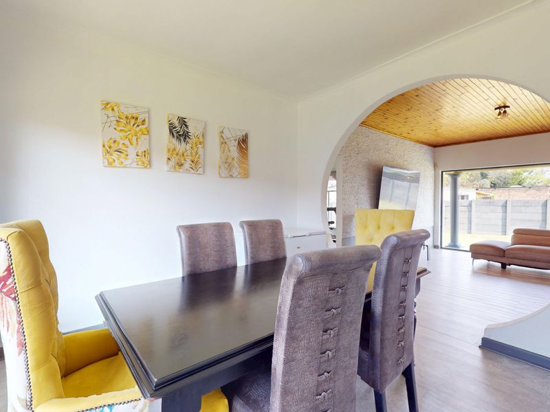 Dining area featuring a distinctive circular archway leading to an adjacent living space with a timber-clad ceiling and stone feature wall.