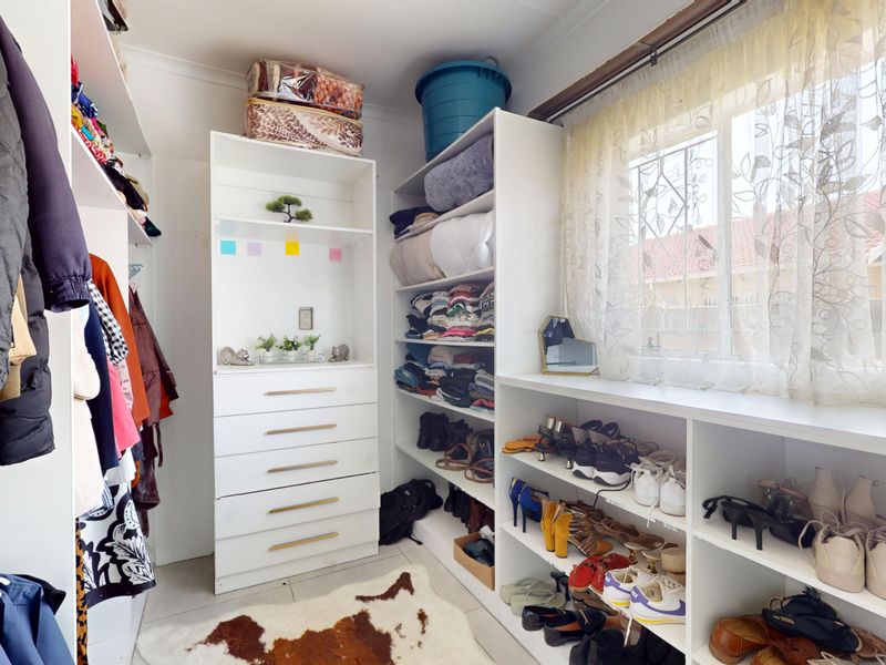 A walk-in closet or dressing room featuring extensive built-in white cabinetry and shelving units for organized storage.