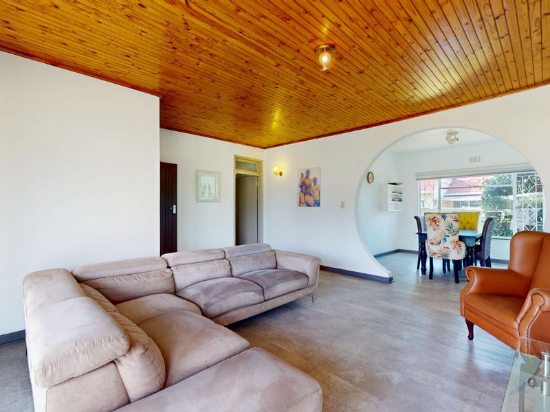 Open plan living and dining area featuring a distinctive timber tongue and groove ceiling and a large circular archway connecting the spaces.