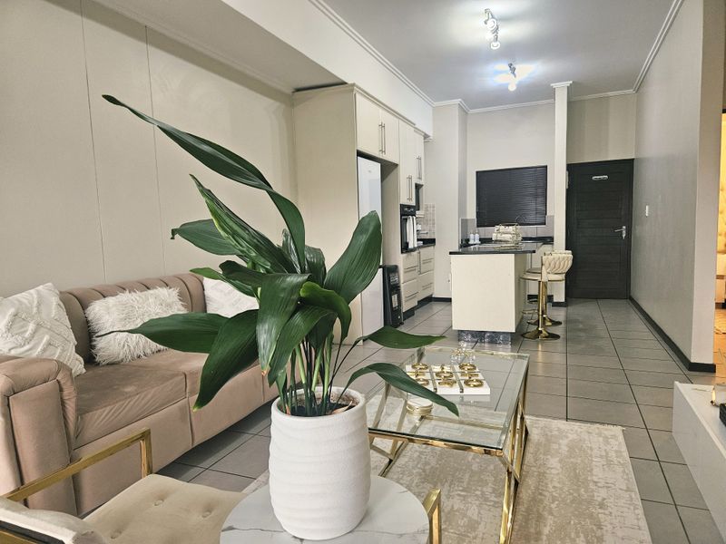 Open plan living area featuring a modern kitchen with island, tiled flooring, and neutral wall finishes, creating a cohesive and functional living space.