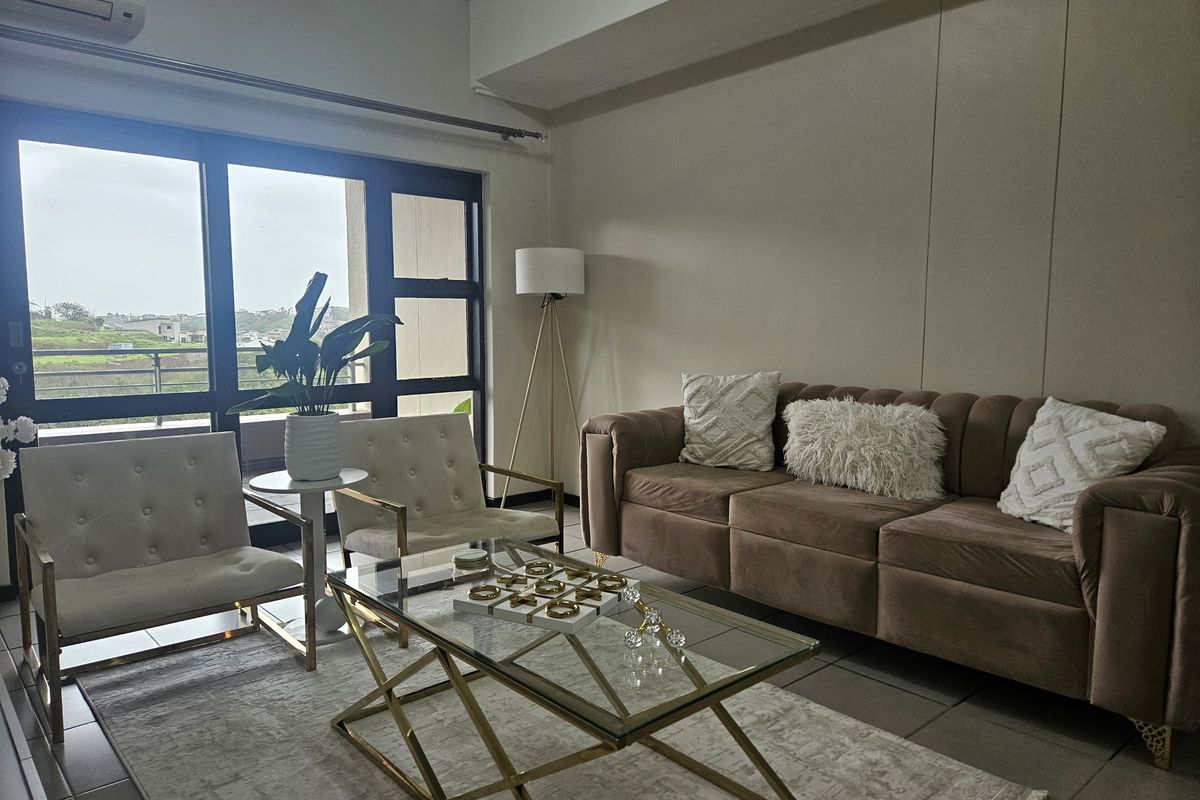 A bright living room featuring large sliding glass doors that provide natural light and access to an outdoor area, complemented by tiled flooring.