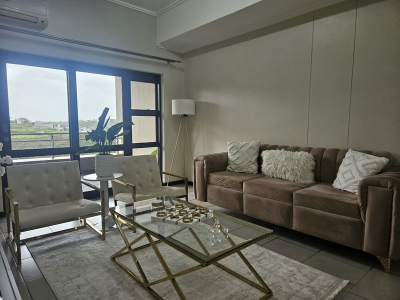A bright living room featuring large sliding glass doors that provide natural light and access to an outdoor area, complemented by tiled flooring.