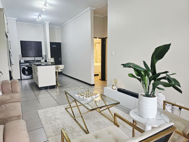 An open-plan living area featuring tiled floors, a modern kitchen island with integrated appliances, and a seamless flow into the adjacent living space.