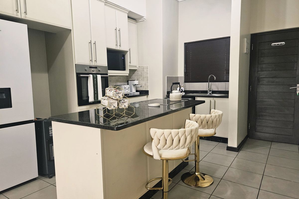Modern kitchen featuring granite countertops, a central island with breakfast bar, built-in oven, microwave, and tiled flooring.