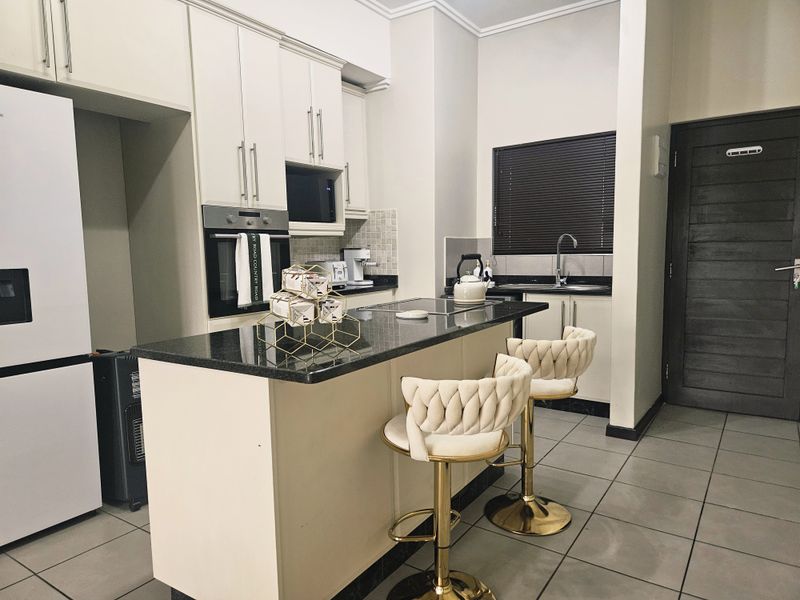 Modern kitchen featuring granite countertops, a central island with breakfast bar, built-in oven, microwave, and tiled flooring.