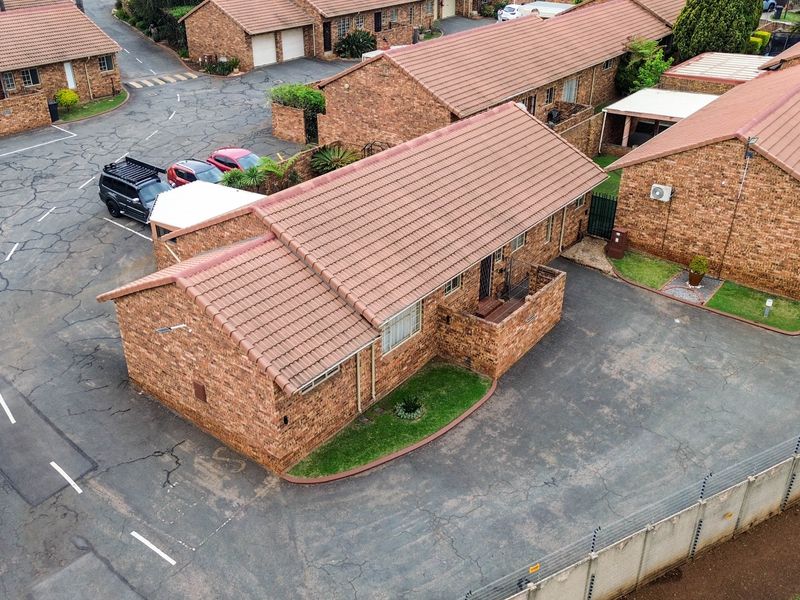 Aerial view of a facebrick townhouse complex featuring tiled roofs, paved driveways, and perimeter electric fencing.