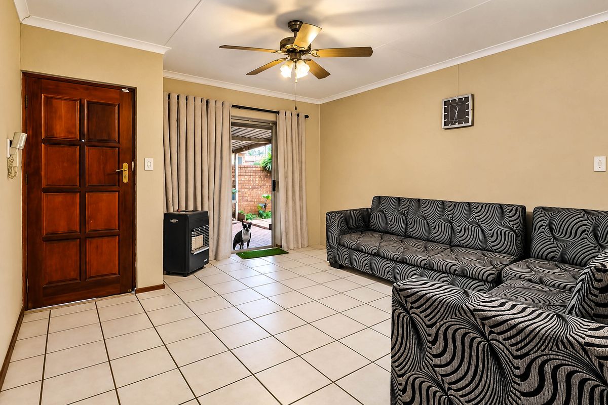 A living room featuring tiled flooring, a ceiling fan, and a sliding glass door providing access to the rear patio area.