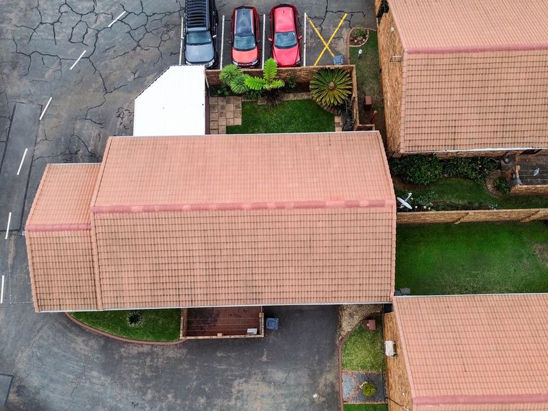 Aerial view of the townhouse complex showing tiled roof structures, private garden spaces, and paved driveway areas.