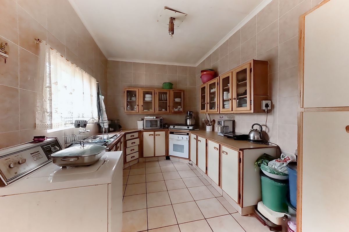 A dated kitchen featuring tiled walls and floors, built-in cabinetry, and an integrated oven, offering significant potential for a modern renovation.
