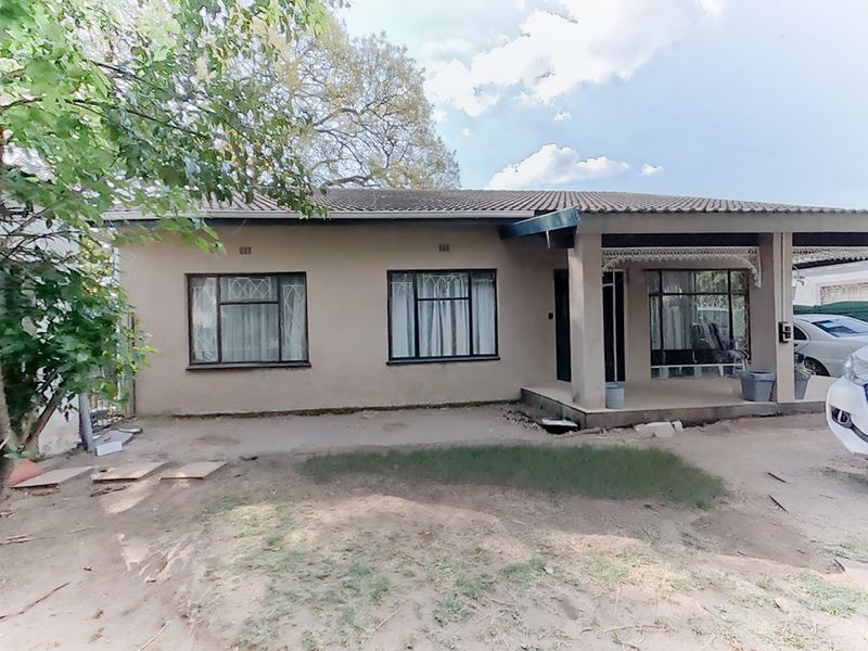 Front elevation of a single-story house featuring a tiled roof, covered patio area, and a concrete driveway.