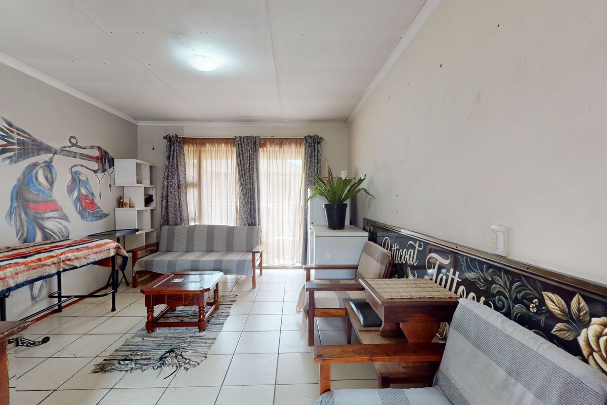 A living room area featuring tiled flooring and a sliding glass door, requiring cosmetic updates to the wall finishes.