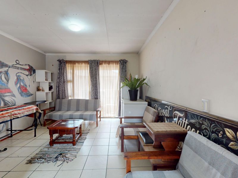 A living room area featuring tiled flooring and a sliding glass door, requiring cosmetic updates to the wall finishes.