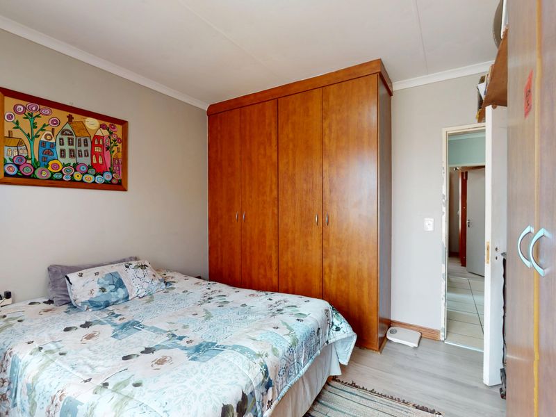 A bedroom featuring built-in wooden wardrobes, laminate flooring, and coved ceiling details, providing a functional and neutral living space.