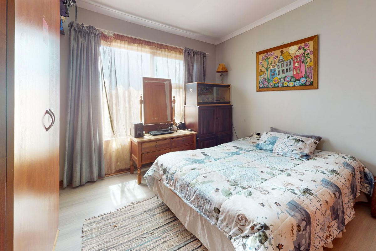 A functional bedroom featuring laminate flooring, coved ceilings, and a built-in wardrobe, offering a comfortable and well-lit living space.