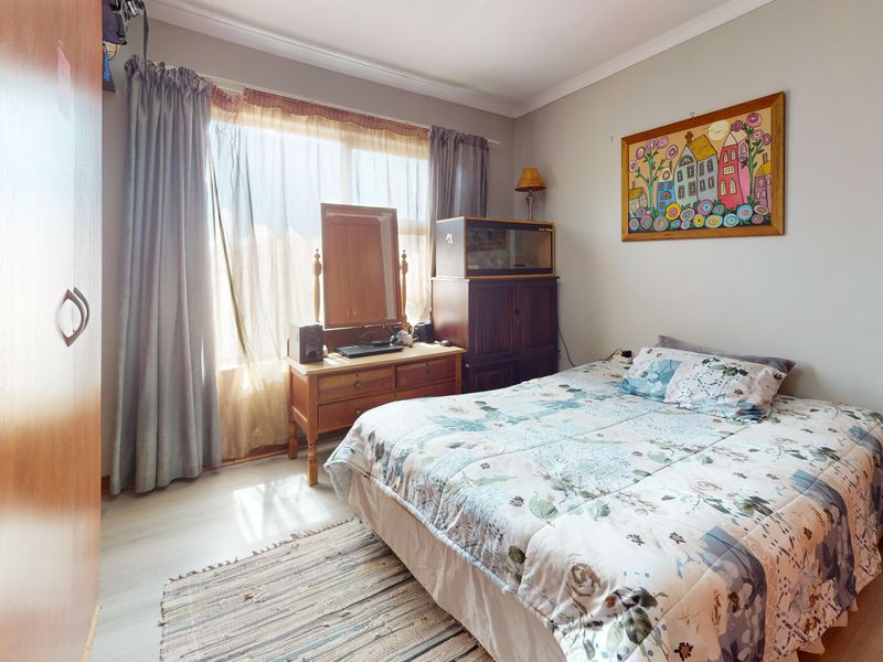 A functional bedroom featuring laminate flooring, coved ceilings, and a built-in wardrobe, offering a comfortable and well-lit living space.