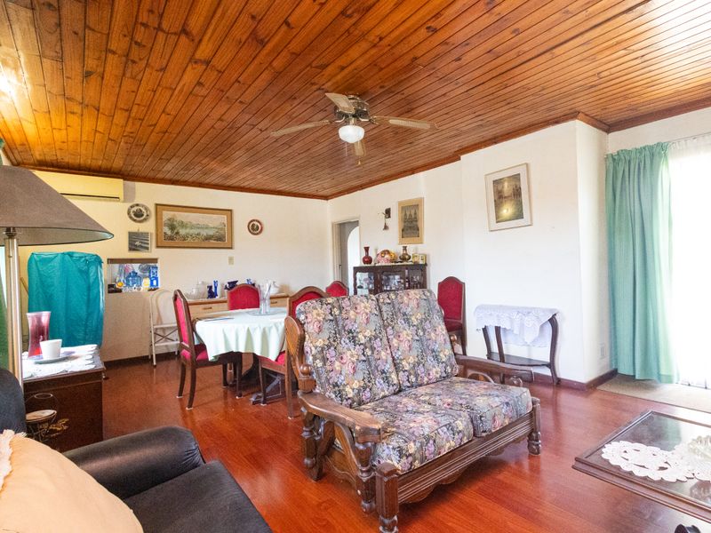 Open plan living and dining area featuring timber panelled ceilings, ceiling fan, and laminate flooring with access to an outdoor area.