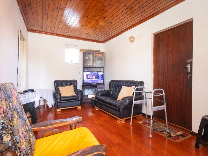 A living room featuring timber panelled ceilings, laminate flooring, and a solid timber entrance door.