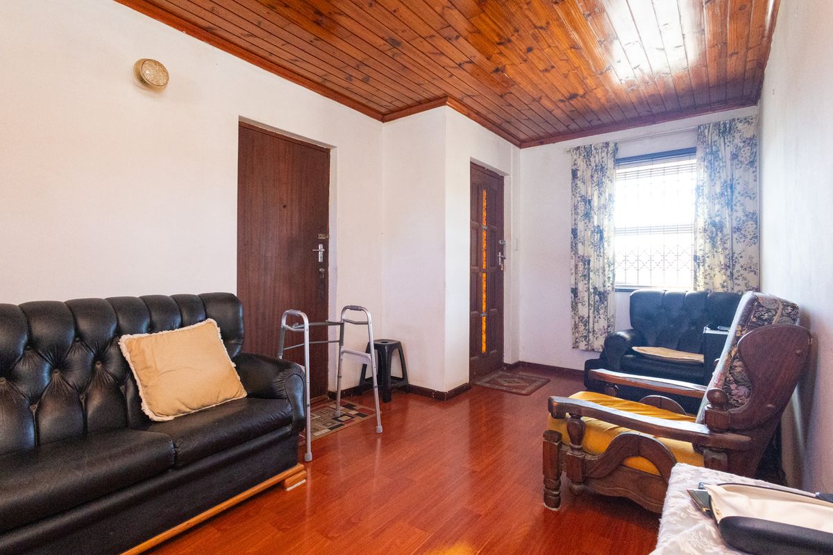 A living room featuring a timber-paneled ceiling, laminate flooring, and solid wood doors, offering a traditional layout with natural light.