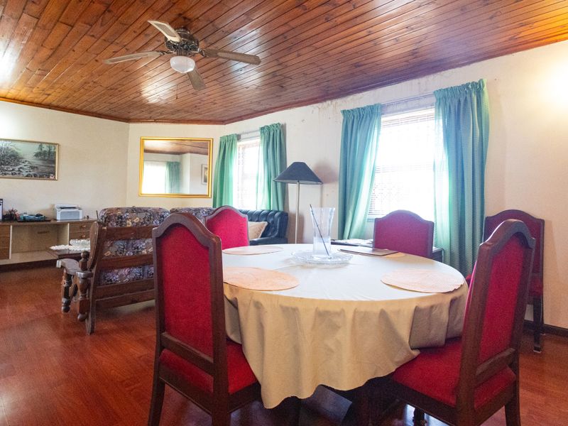 Open plan living and dining area featuring timber ceilings, ceiling fan, laminate flooring, and a built-in desk unit.