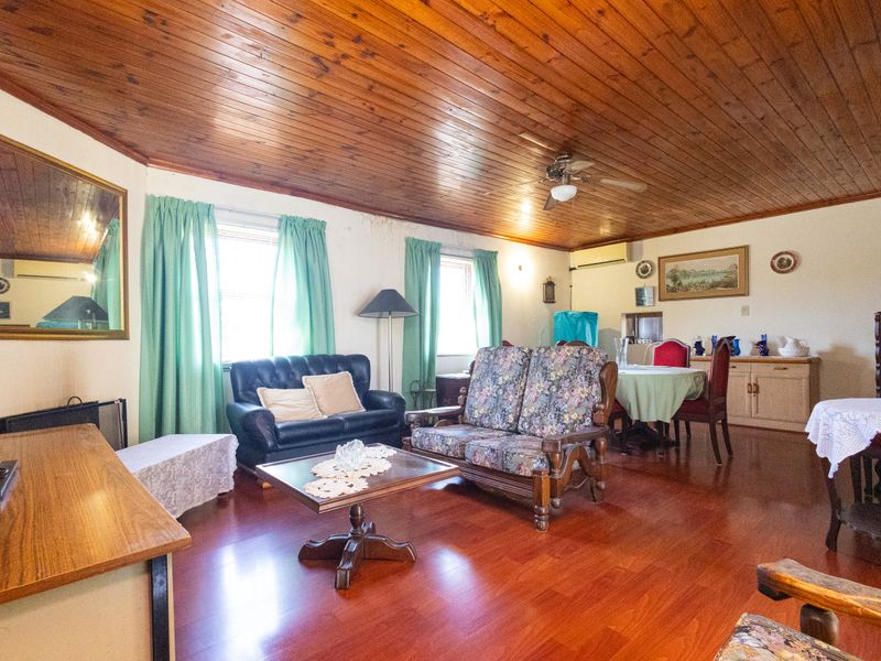 Open-plan living and dining area featuring timber ceilings, laminate flooring, and a wall-mounted air conditioner.