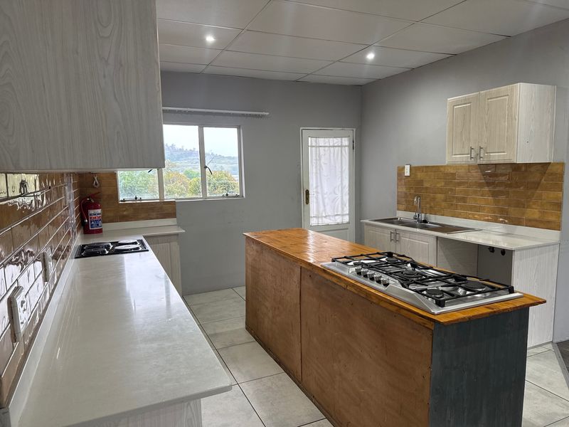 A spacious kitchen featuring dual hobs, ample cabinetry, tiled backsplash, and a central island, offering a functional layout ready for modern updates.