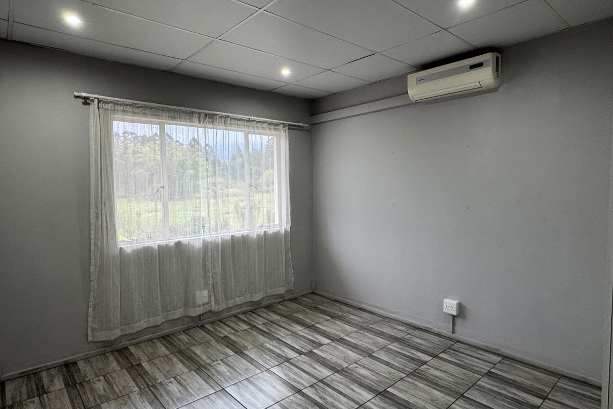 An empty bedroom featuring tiled flooring, a drop ceiling with recessed lighting, and a wall-mounted air conditioning unit.