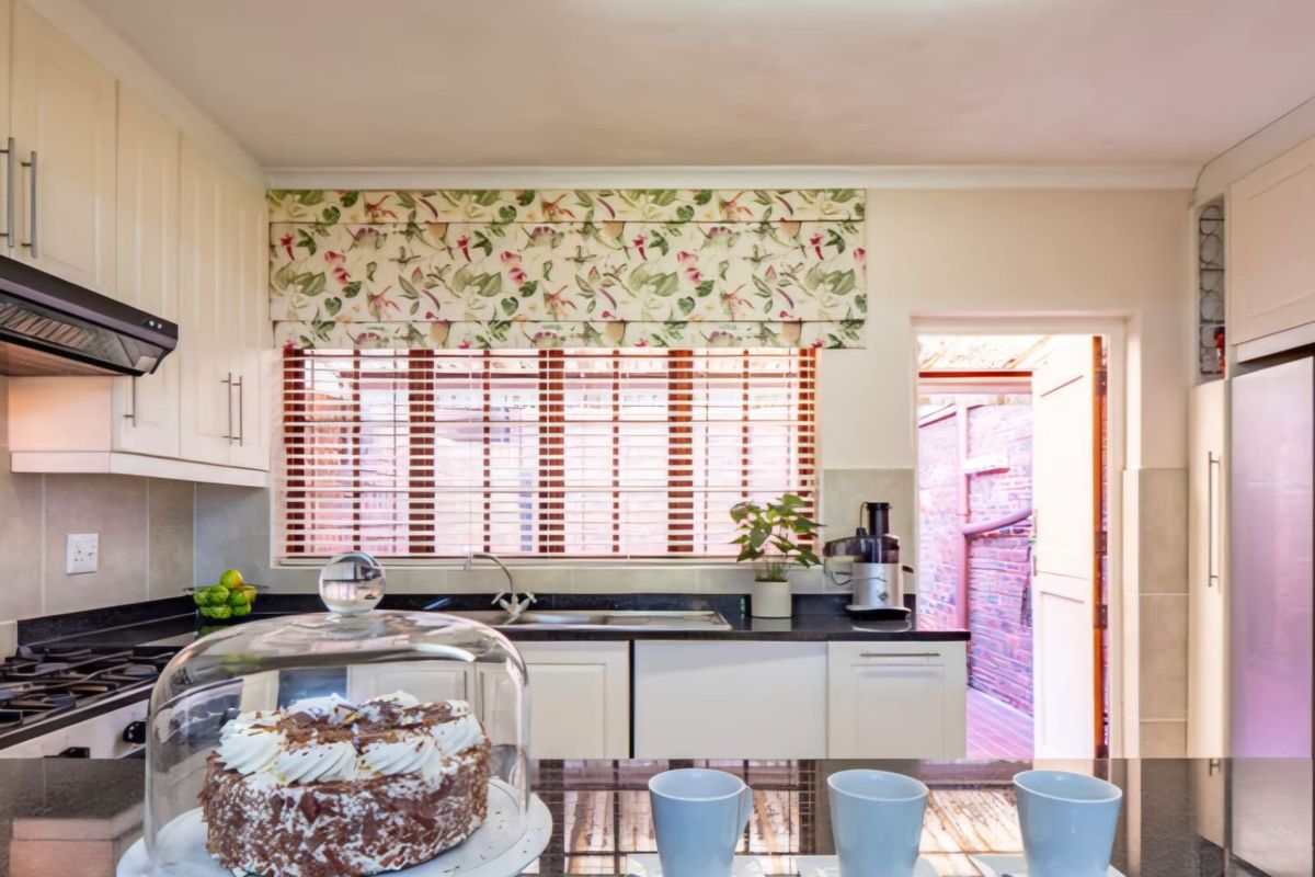 A well-maintained kitchen featuring granite countertops, built-in cabinetry, a gas hob with extractor fan, and direct access to an outdoor area.