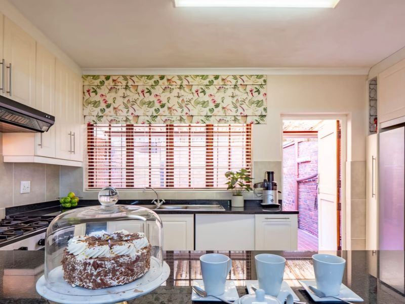 A well-maintained kitchen featuring granite countertops, built-in cabinetry, a gas hob with extractor fan, and direct access to an outdoor area.