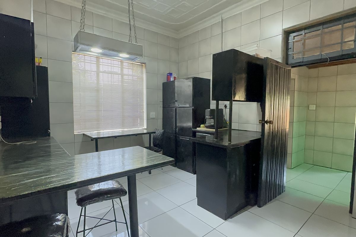 A functional kitchen featuring tiled walls and flooring with built-in cabinetry and an overhead extractor fan, offering potential for modern updates.