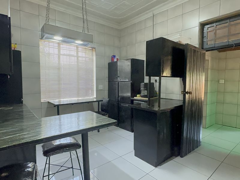 A functional kitchen featuring tiled walls and flooring with built-in cabinetry and an overhead extractor fan, offering potential for modern updates.