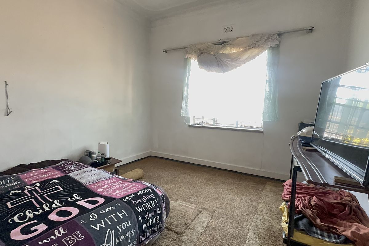 A bedroom featuring carpeted flooring and a window with a curtain rod, requiring cosmetic updates to improve its overall condition and appeal.