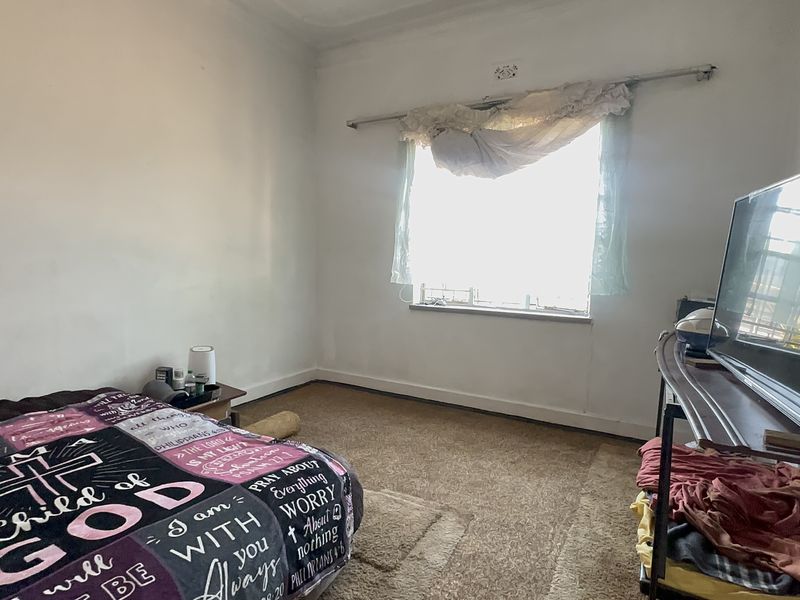 A bedroom featuring carpeted flooring and a window with a curtain rod, requiring cosmetic updates to improve its overall condition and appeal.