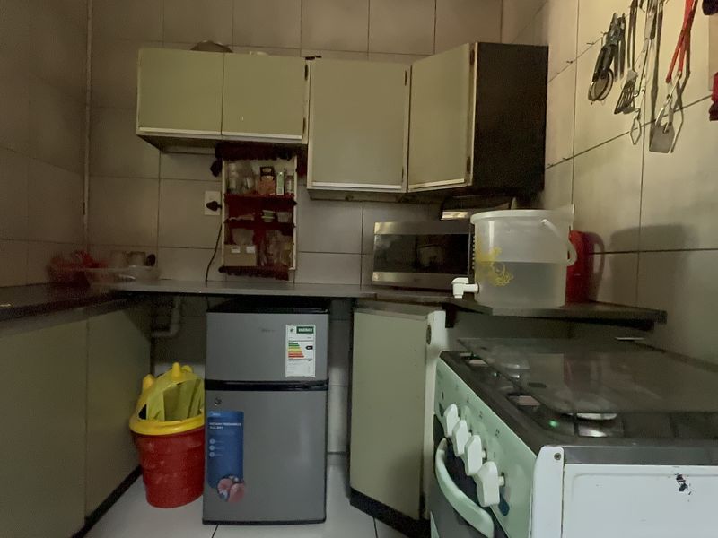 A compact kitchen featuring tiled walls, built-in cabinetry, and a freestanding stove, offering a functional layout with potential for modernization.