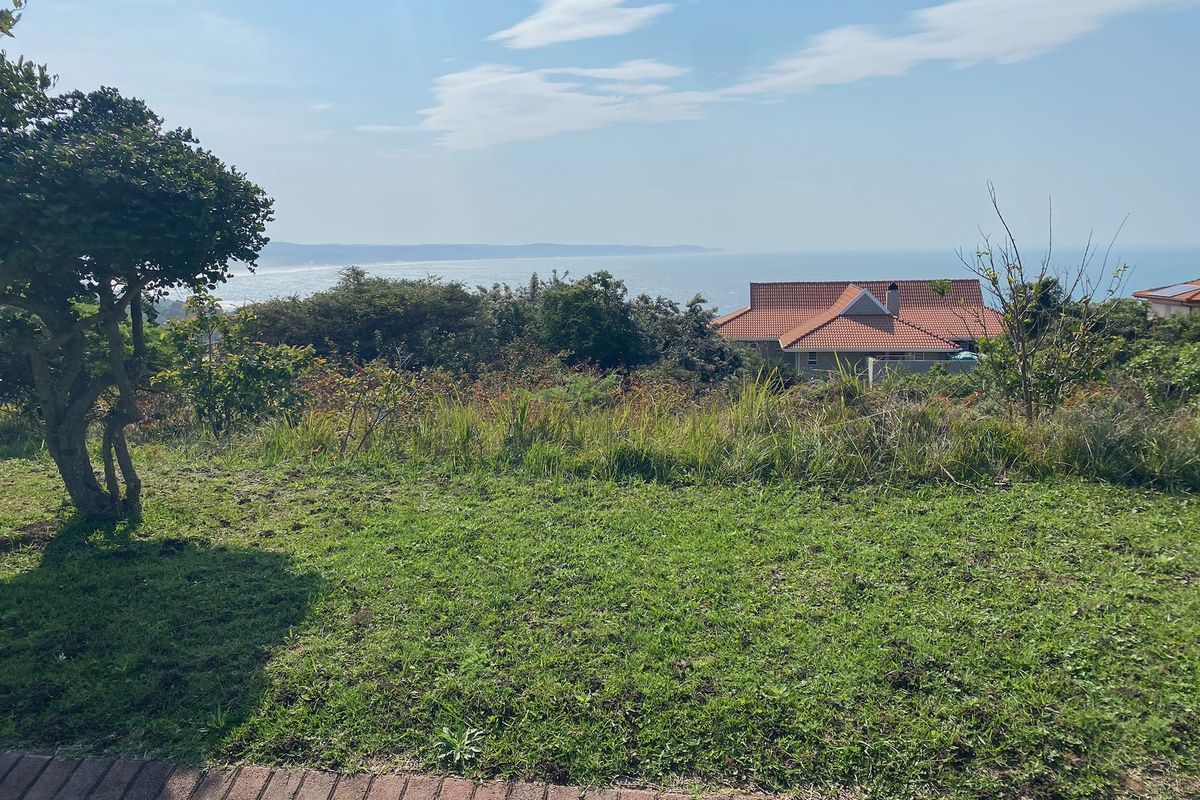 A scenic view overlooking a coastal landscape with natural vegetation and a distant residential property.